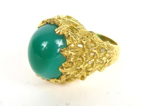 Bague en or jaune, belle monture moderne retenant une pierre verte en 