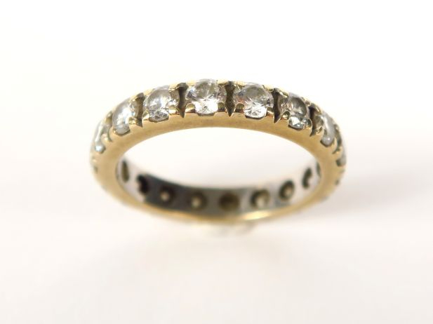 Bague en or jaune, belle monture moderne retenant une pierre verte en 