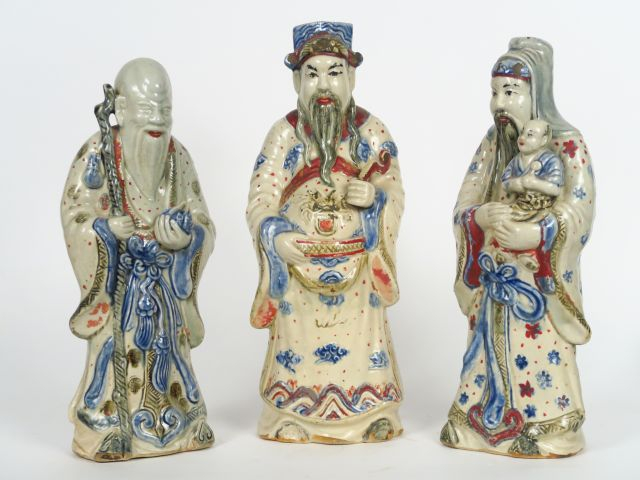 Trois statuettes en faïence émaillée en bleu sur fond crème et rehauss