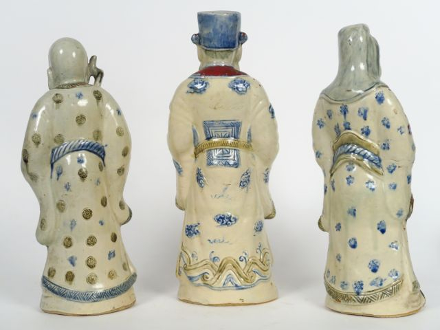 Trois statuettes en faïence émaillée en bleu sur fond crème et rehauss