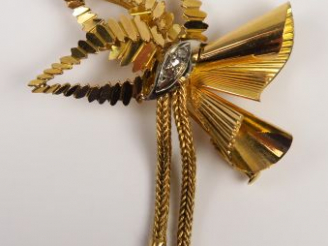 Vente aux enchères Broche en or deux tons figurant un noeud stylisé, serti de petites ros