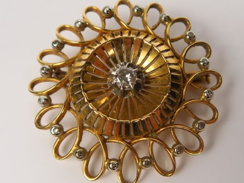 Broche ronde en or à décor d'entrelacs, ornée d'un diamant central et 
