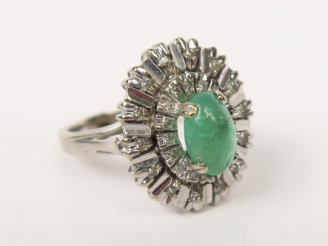 Vente aux enchères Bague en or gris ornée d’un cabochon d’émeraude sur un décor rayonnant