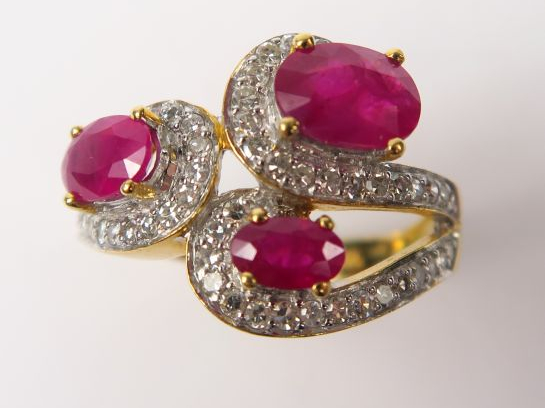 Bague ornée de trois rubis, soulignés par des lignes de diamants. Mont