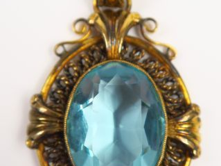 Vente aux enchères Pendentif en métal doré orné d'une pierre de couleur