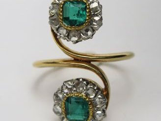 Bague ornée de deux émeraudes carrées dans un entourage de diamants ta