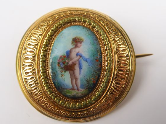 Broche ronde à décor d'une plaque émaillée figurant un amour. Poids te