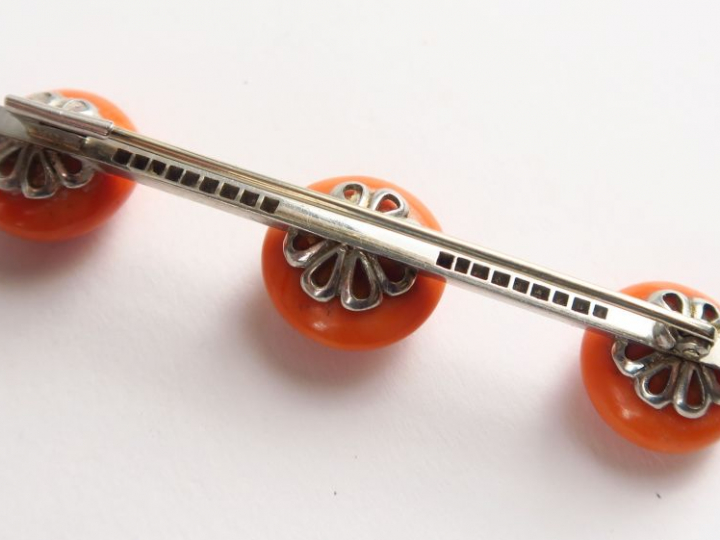 Broche ornée de trois boutons de corail, monture en or blanc sertie de