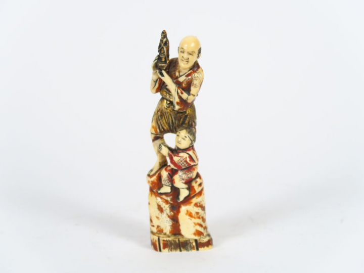 Okimono en ivoire marin polychrome représentant un homme tenant une st