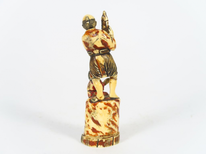 Okimono en ivoire marin polychrome représentant un homme tenant une st