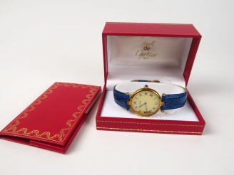Vente aux enchères CARTIER. Montre 'Must', boitier en vermeil, bracelet en cuir bleu