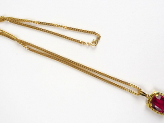 Vente aux enchères 12/ Chaine en or (13 g), retenant un pendentif en or serti d'un rubis 