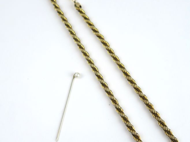 Epingle de cravate en or blanc, ornée d'une perle. Poids tel : 1,25 g.