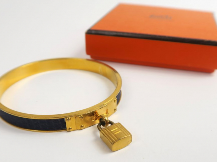 HERMES. Bracelet kelly en métal doré et cuir (usures)