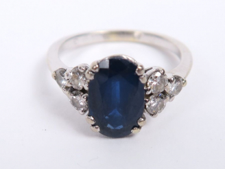 Vente aux enchères Bague en or blanc, ornée d'un saphir épaulé de trois diamants de chaqu