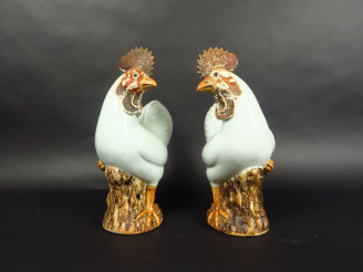 Vente aux enchères Paire de coqs en porcelaine émaillée blanc et brun, debout sur des roc