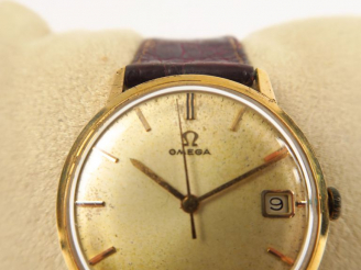 Vente aux enchères OMEGA. Montre  boitier or, guichet date. Diam. 35 mm  (cadran à nettoy