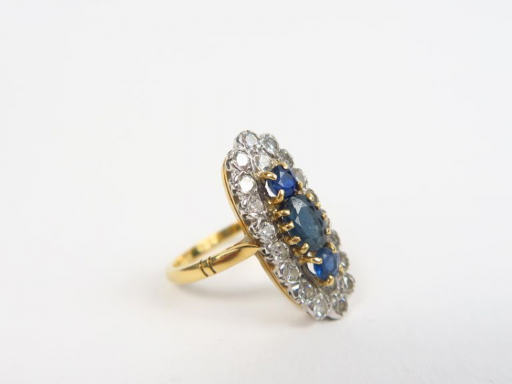 Bague marquise en or ornée de trois saphirs et entourage de petits bri