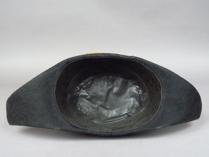 Bicorne en taupé noir, sans galon, bouton à décor de couronne de lauri