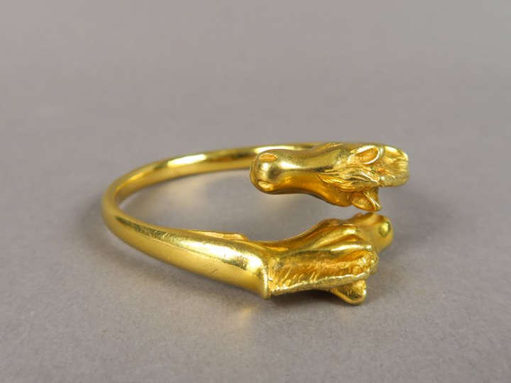 HERMES.  Bracelet jonc en métal doré, à décor de chevaux.  Signé.