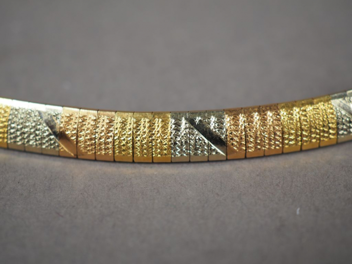 Collier articulé trois ors, à décor de motifs géométriques.  Poids. 36