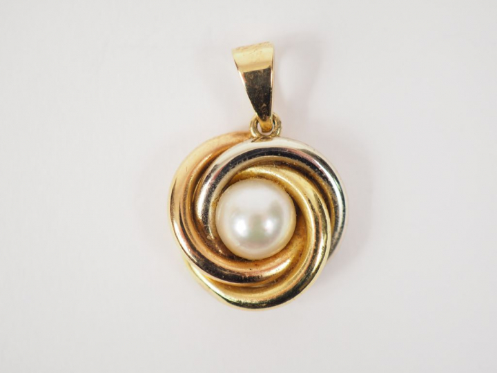 Pendentif trois tons d'or, orné en son centre d'une perle.  Poids tel.