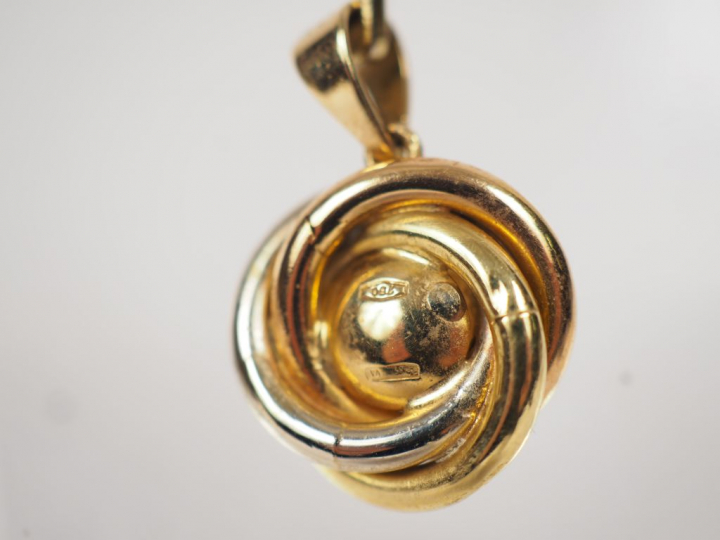 Pendentif trois tons d'or, orné en son centre d'une perle.  Poids tel.