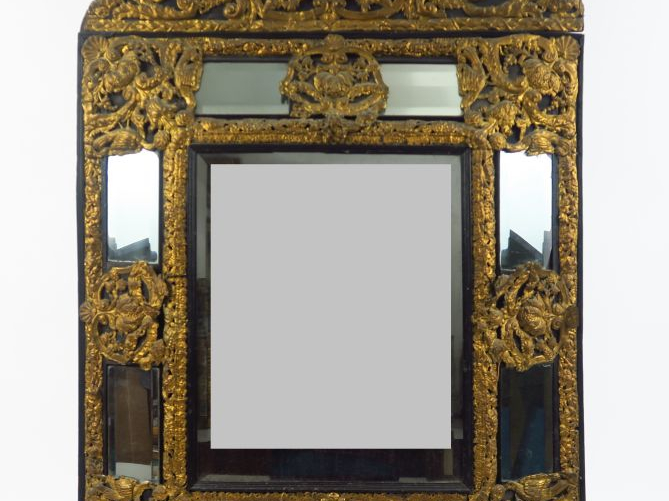 Glace à parecloses Louis XIV en bois noirci et laiton repoussé à décor