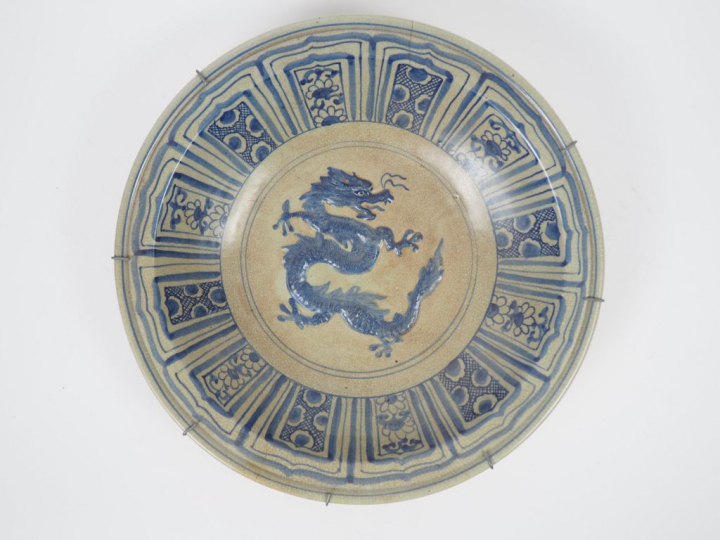 Plat en céramique émaillée beige et bleu, à décor en relief d'un drago