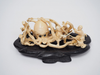 Vente aux enchères Okimono en ivoire représentant des pêcheurs attaquant un poulpe géant.