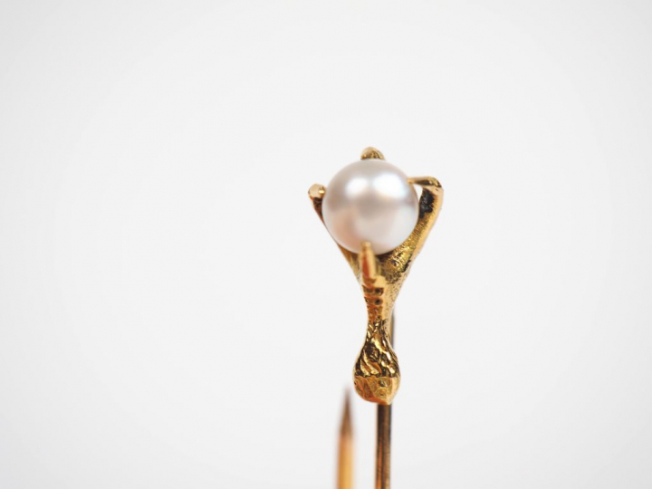 Epingle en or jaune figurant une patte tenant une perle. Poids. 1,87 g