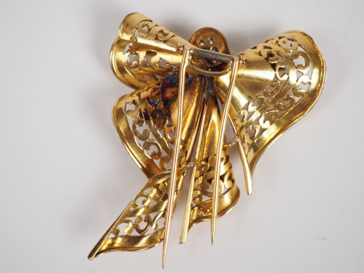 Broche en or jaune, en forme de ruban stylisé, à décor en son centre d