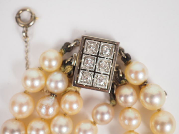 Collier de perles triple rangs.  Fermoir en or blanc orné de six petit