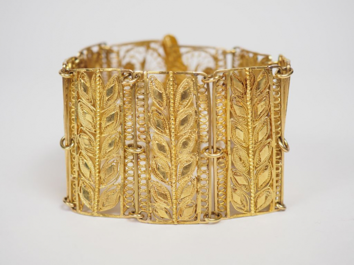 Bracelet manchette en or jaune, à décor ajouré et filigrané de feuilla