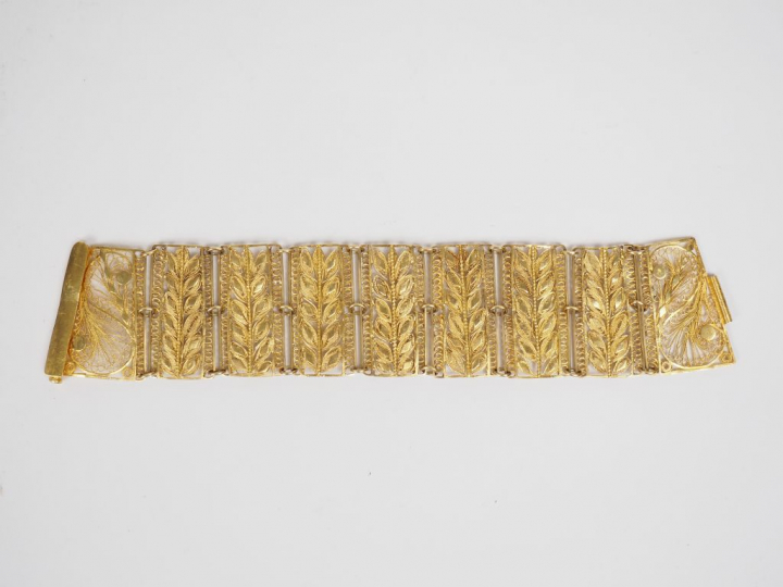 Bracelet manchette en or jaune, à décor ajouré et filigrané de feuilla