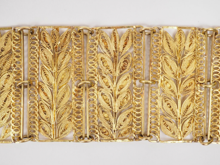 Bracelet manchette en or jaune, à décor ajouré et filigrané de feuilla