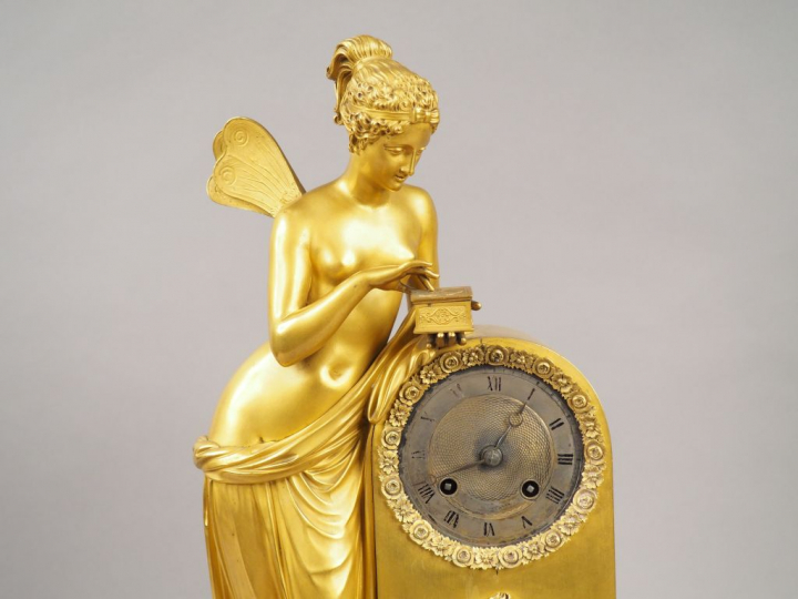 Pendule XIXème en bronze doré, à décor d'une femme ailée ouvrant un co