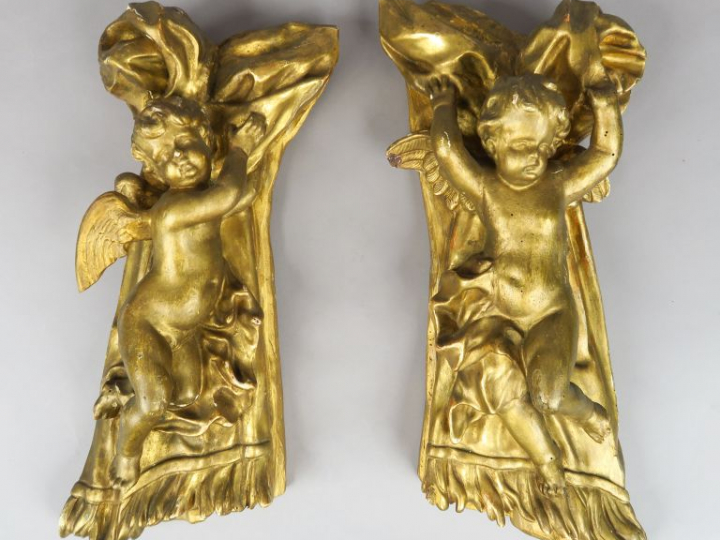 Paire d'anges XIXème en bois et stuc doré, se détachant sur fond de dr