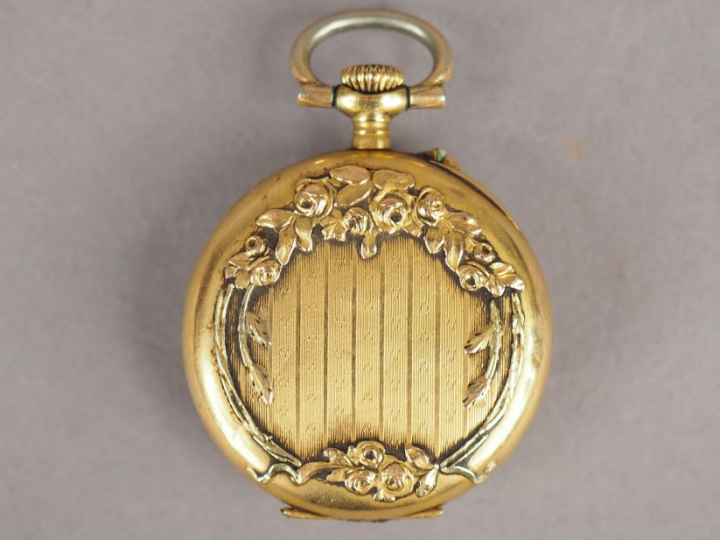 Montre de col en or jaune, cadran émaillé, chiffres arables.  Le rever