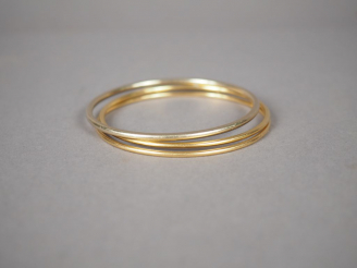 Vente aux enchères Ensemble de trois joncs dont deux en or jaune et un en or blanc. Poids