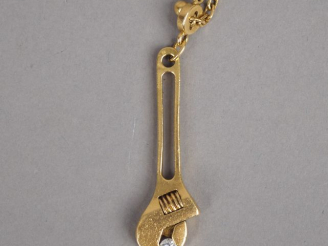 Vente aux enchères G. JONEMANN Pendentif en or jaune en forme de clé à molette serrant un