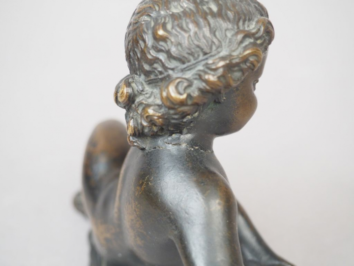 Enfant allongé en bronze patiné. XIXème siècle. H. 12 cm (fissure au c