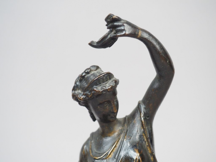 Femme drapée à l’antique tenant une lampe à huile en bronze patiné. Dé