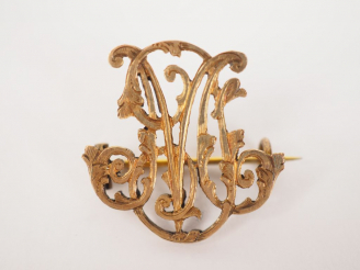 Vente aux enchères 	Broche en or jaune, à décor de monogramme. 3 x 2,5 cm  Poids. 5.15 g