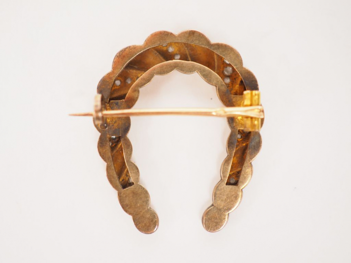 Petite broche en or jaune et diamants en forme de fer à cheval.  Poids