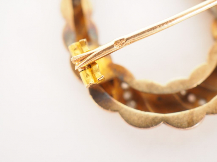 Petite broche en or jaune et diamants en forme de fer à cheval.  Poids
