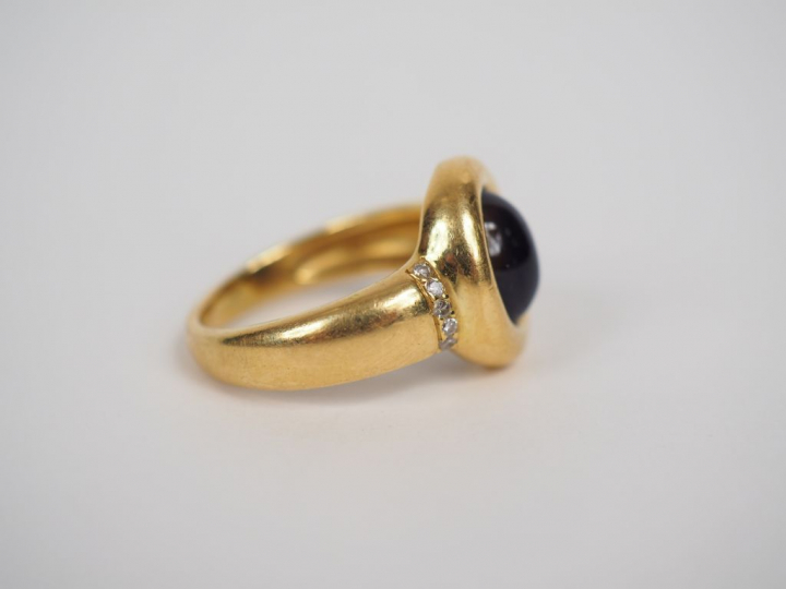 Bague en or jaune orné en son centre d'une pierre violette en cabochon