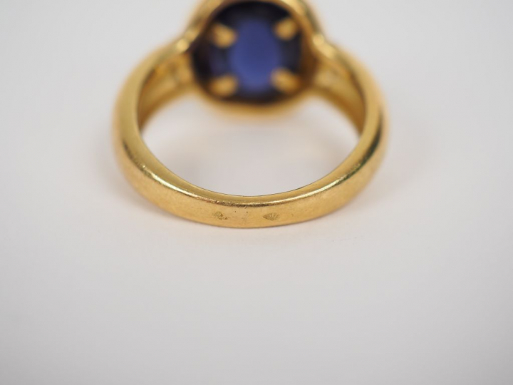 Bague en or jaune orné en son centre d'une pierre violette en cabochon