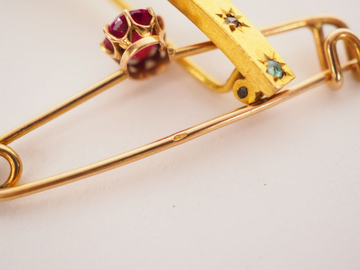 Broche en or jaune, ornée d’une pierre de couleur. Poids tel. 1.65 g	 