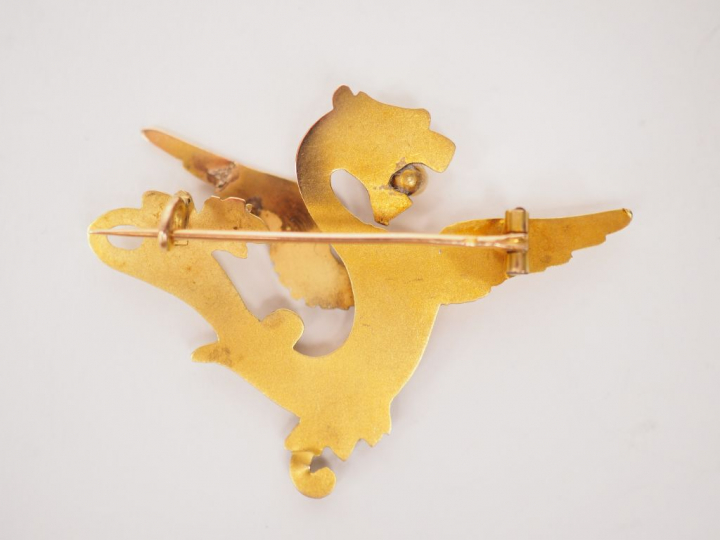 Broche en or jaune en forme de chimère tenant dans sa gueule une perle